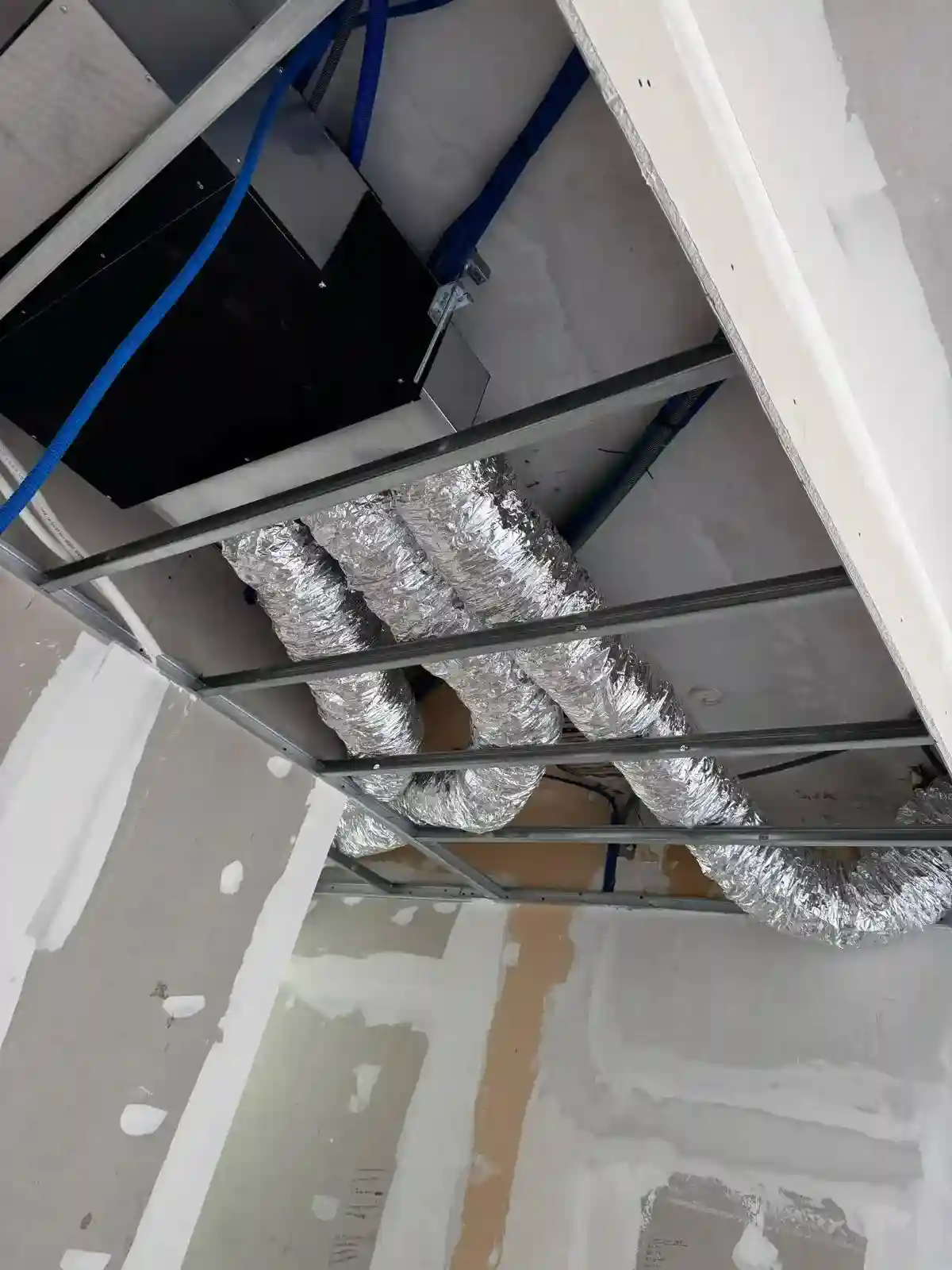 Une équipe de techniciens installant et vérifiant une unité de climatisation intérieure.