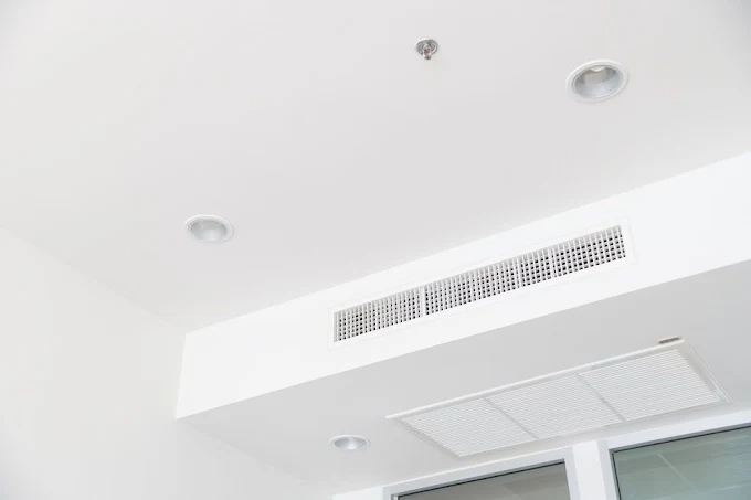 Grille de soufflage et filtre à air d'un système de climatisation au plafond minimaliste.