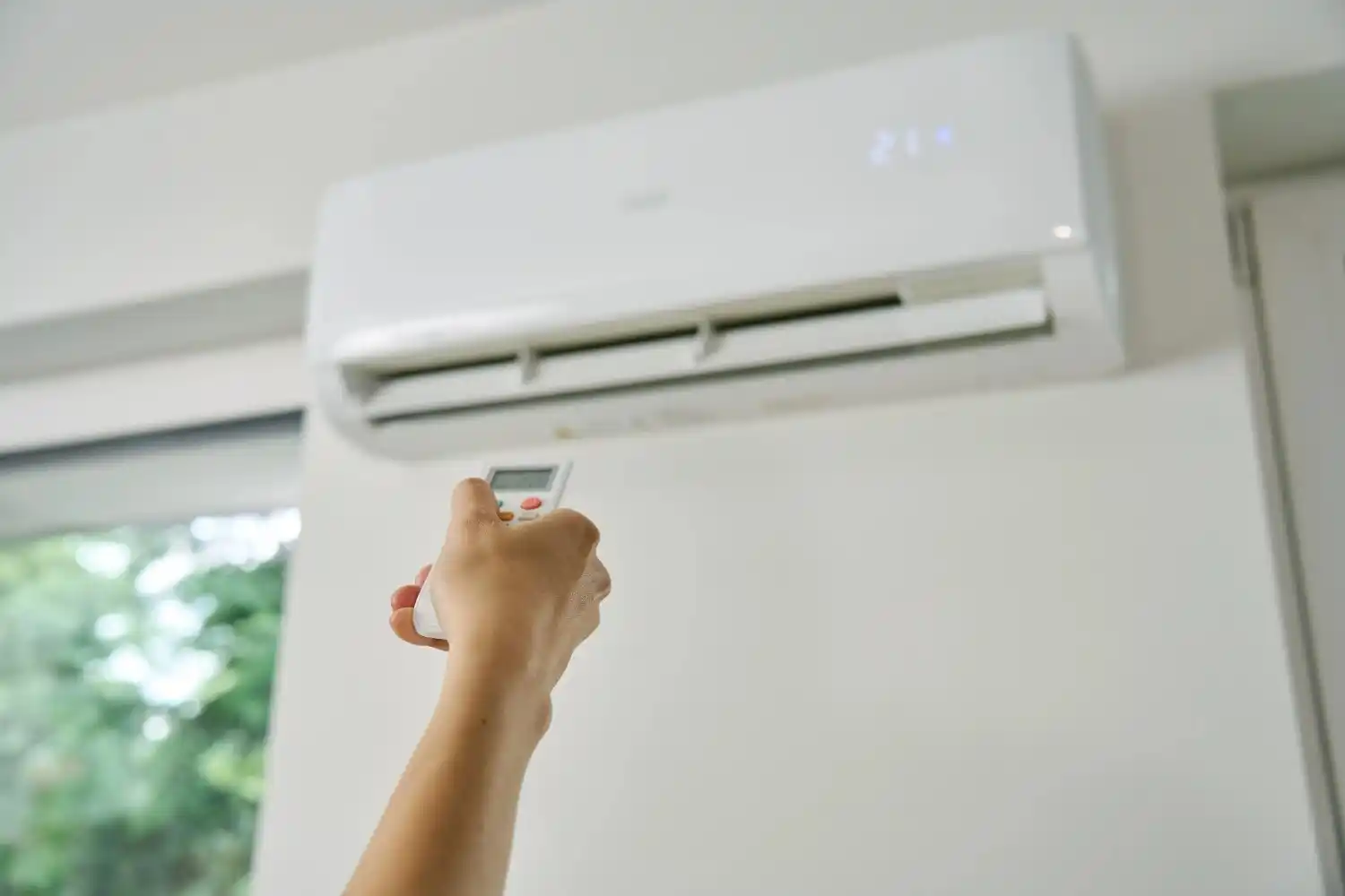 Quelqu'un allumant le climatiseur à l'aide d'une télécommande.